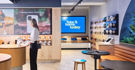 retail image of customer in an Optus outlet with large screens in background