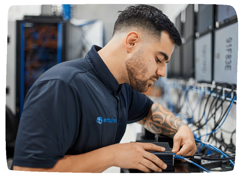 Close up of a entwined staff member working on a chrome OS box, plugging in cords to the back of it. 