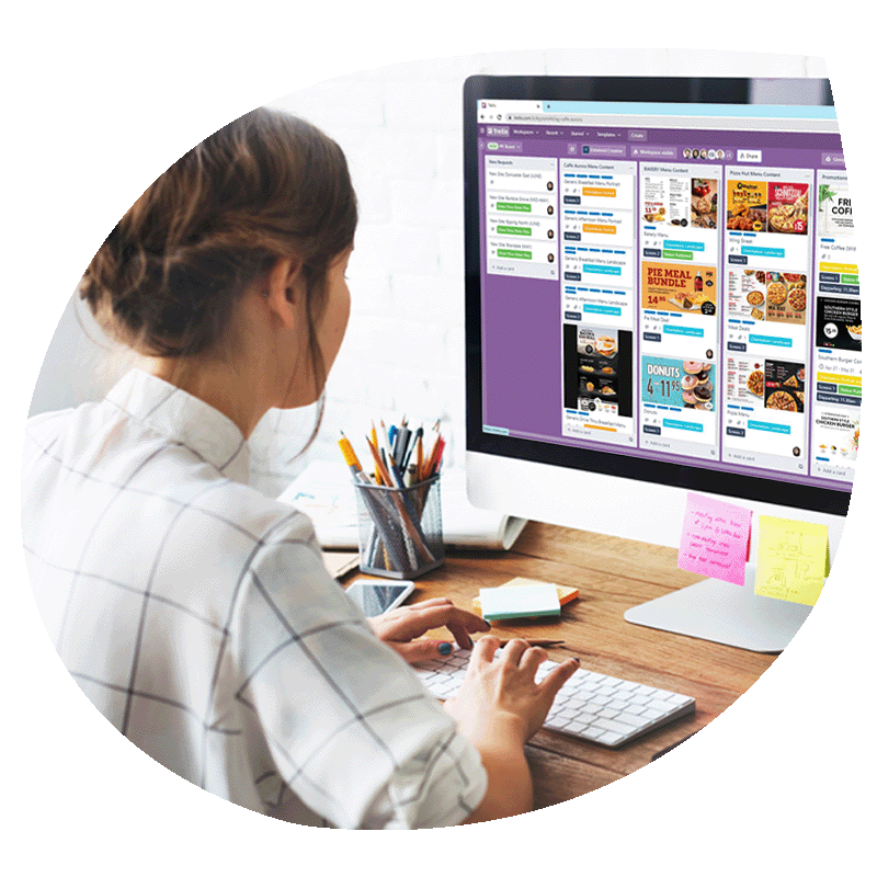 A girl sitting at a desk working on a computer, the computer has a series of tasks along its monitor.