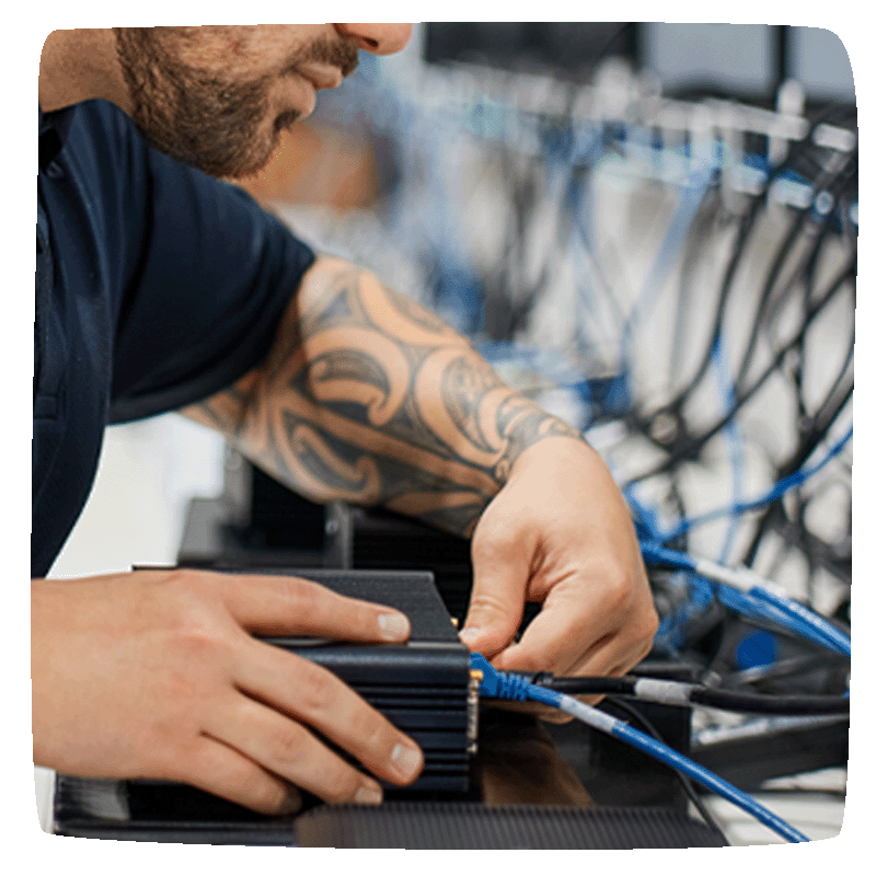 Close up of a entwined staff member working on a chrome OS box, plugging in cords to the back of it. 