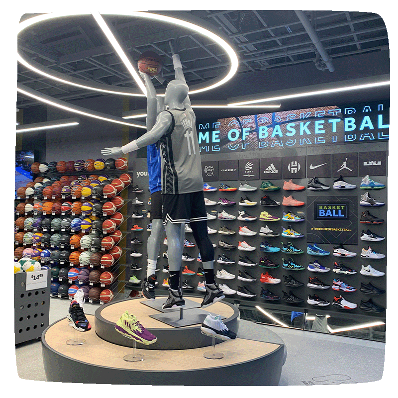 An image of a rebel basketball section, with two mannequins pretending the play basketball and wall of shoes behind them.