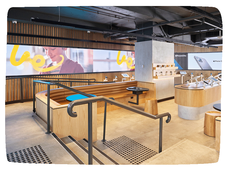 Shot of an the inside of an Optus store. A large curved LED wall at the back wraps around the various phones and tables attached to desks around the building. 