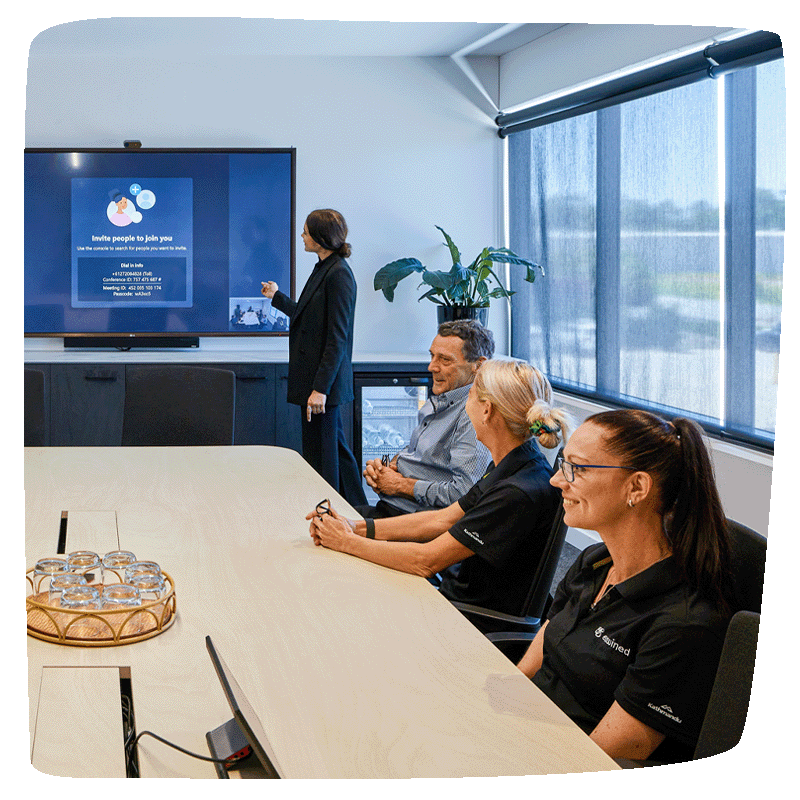 A presentation being made in an office setting with 3 people sitting at a desk looking on.